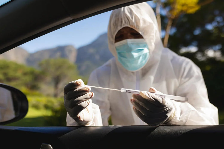 A person wearing personal protection clothes checking a person in a car